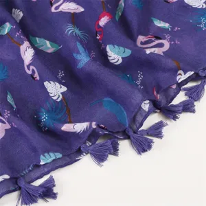 Primo piano della sciarpa viola con stampa di fenicotteri e foglie e nappe coordinate.
