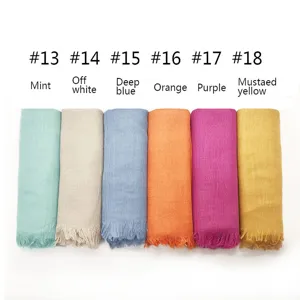 Detailed view of rolled cotton blend scarves in assorted vibrant colors with fringe, close-up.