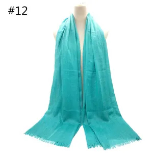 Turquoise color detail of solid cotton scarf with short fringe, soft breathable fabric texture.