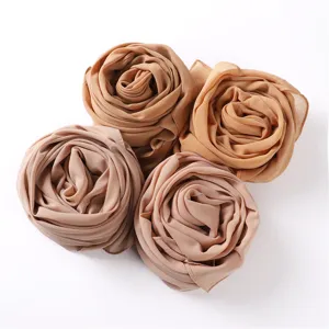 Nahaufnahme gerollter Chiffon Hijab Schals in sanften Beigetönen, feine Stoffstruktur im Detail.