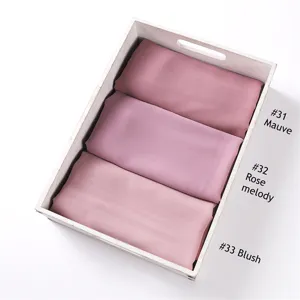 Detailansicht von einfarbigen Chiffon Hijab Schals, ordentlich in einem Holztablett platziert.