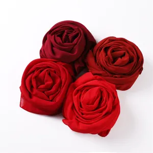 Detailansicht gerollter roter Chiffon Kopftücher in Rosenform mit weicher Stoffqualität.