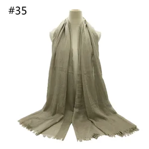 Detail of a breathable solid color cotton blend scarf featuring short fringe and oversized design.