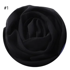 Schwarzer Chiffonstoff zu einer Rosenform gerollt, detailgetreue Nahaufnahme des Artikels.