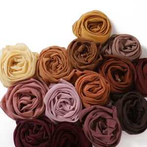 Close-up detail of soft chiffon headscarves rolled in rose shapes, breathable lightweight fabric.