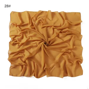 Detail view of a solid yellow chiffon square scarf showing its delicate crinkle texture.