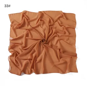 Detail shot of a lightweight chiffon square scarf in solid caramel brown color, soft and airy.