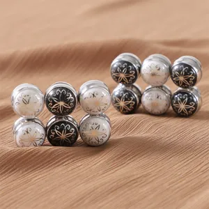 Primo piano di spille magnetiche per hijab, eleganti clip per sciarpa smaltate in bianco e nero.