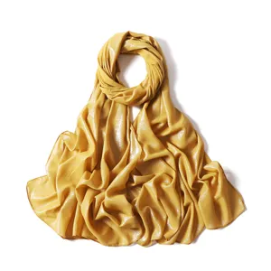 Gold shimmering chiffon hijab detail shot showing sparkling texture and fine fabric finish.