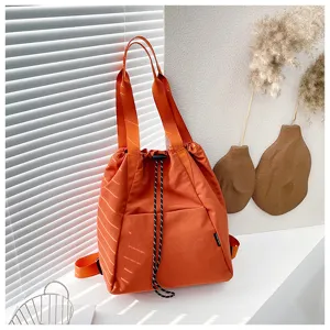 Orange drawstring bucket backpack detail view, casual nylon shoulder bag with straps.