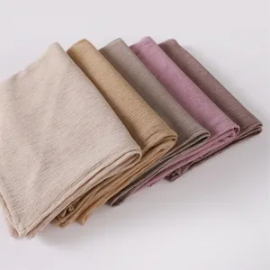 Close-up of folded pleated headscarf detail, showing soft elastic jersey fabric texture and colors.