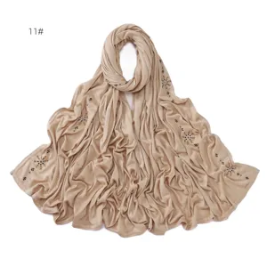 Close-up details of shimmering rhinestone crystal ice flower patterned beige hijab scarf fabric.