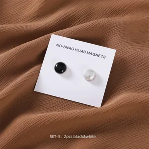 Nahaufnahme Detailansicht runder schwarz-weißer Hijab Magnetknöpfe auf weißer Präsentationskarte.