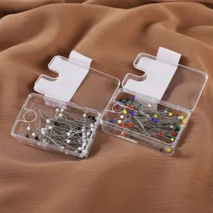 Dettaglio di spilli con testa di vetro colorata e bianco nero in scatole trasparenti.