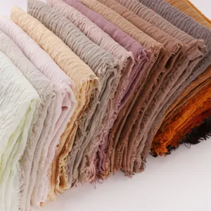 Detailed close-up view of stacked multi-color crinkled cotton linen scarves with soft texture.