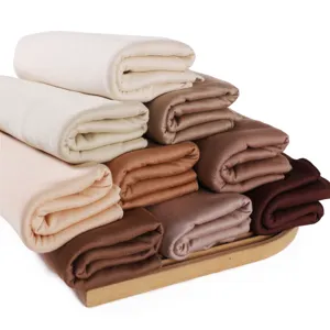 Detail shot of folded soft solid color jersey modal scarfs stacked neatly on a tray.