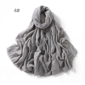 Detail view of a gray crinkled cotton linen scarf featuring soft texture and stylish fringe edges.