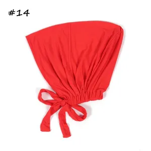 Detail van rode ademende elastische modal muts met strikband, zachte comfortabele ondercap.