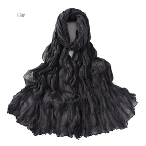 Detail shot of a dark grey crinkled lightweight sheer scarf, fine textured fabric.