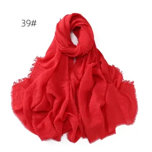 Detail view of the solid red cotton linen crinkled scarf with stylish frayed fringe edges.