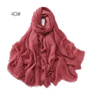 Detail view of the crinkled cotton linen scarf texture, showing soft frayed fringe edges clearly.