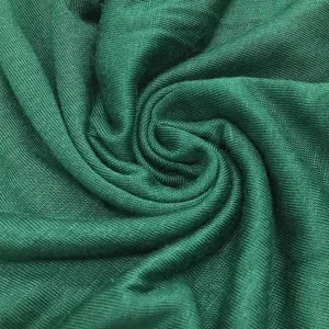 Close-up view of soft green modal fabric showing elastic knitted texture and smooth surface.