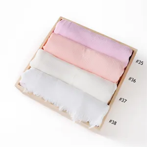 Detailed view of solid color soft crinkle rayon scarf with short tassels in wooden tray.