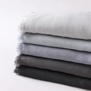 Close-up detail of stacked 100% rayon scarves with natural wrinkles and short fringes.