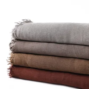 Detailed shot of soft natural wrinkle rayon scarves stacked in various solid colors with short fringe.