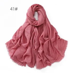 Close up detail of solid pink crinkled cotton linen scarf with fine tassel fringe edge.