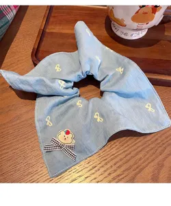 Primer plano detallado del coletero de mezclilla azul con estampado de lazo y parche de oso.