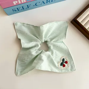 Detalles del bonito coletero de tela verde con un adorable diseño de bordado de cerezas.