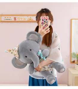 Détail de jouet en peluche éléphant gris avec tissu doux, chapeau floral et pendentif.