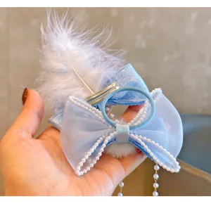 Primer plano detalle de pinza de pelo de lazo de encaje azul con perlas y pluma blanca, accesorio.