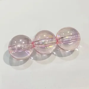 Close-up detail of pink iridescent acrylic round beads with straight holes for DIY jewelry.
