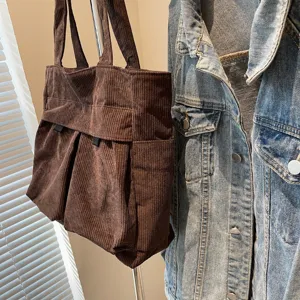 Detail view of brown corduroy tote bag showing large capacity, multiple pockets and fabric texture.