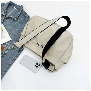 Nylon crossbody bag detail shot, beige casual shoulder bag with black strap for daily use.