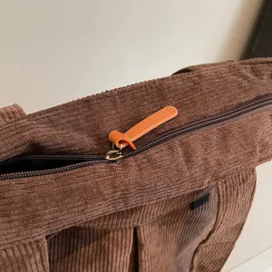 Corduroy shoulder bag zipper detail, brown tote bag texture showcase for daily use.