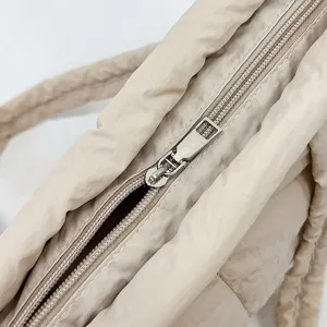 Close-up view of the smooth zipper and soft quilted nylon fabric texture of the casual tote bag.