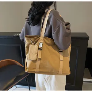 Detailed view of large capacity khaki canvas tote bag with buckle straps and small pouch.