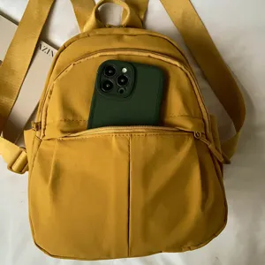 Mini nylon backpack for women, casual yellow travel daypack with front pocket and zipper.