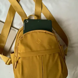 Detailed view of a casual yellow nylon mini backpack, featuring a front pocket and daily storage.