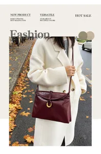 Women's burgundy leather shoulder bag with envelope design and braided ring detail.