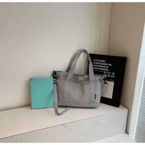 Gedetailleerd overzicht van een minimalisten grijze canvas tote tas met handvatten en riem.