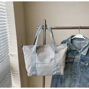 Gedetailleerd overzicht van een minimale effen grijze totebag hanging aan een kledingrek.