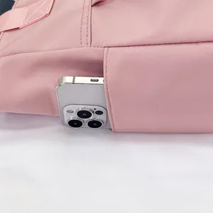 Close up view of pink nylon tote bag side pocket with phone storage detail feature.