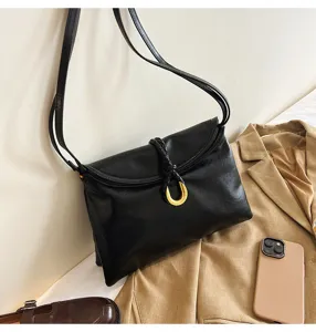 Soft leather shoulder bag detail, elegant black envelope design with golden U-buckle.