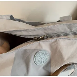 Detailopname van de casual shopper rits en logopatch, minimalistische dagelijkse stijl.