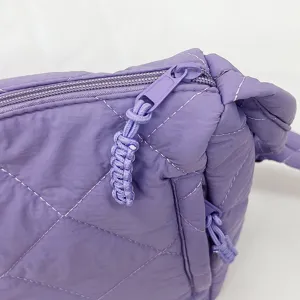 Close-up view of the purple quilted nylon puffer bag detail, showing soft fabric and zipper.