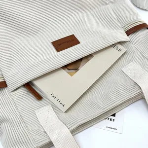 Large capacity beige corduroy tote bag detail showing textured fabric and brown leather accent.